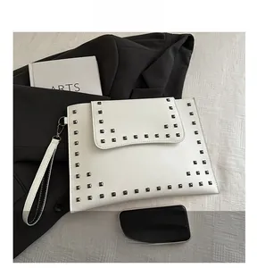 Detailed view of a white envelope clutch bag featuring square silver metal rivets and wristlet