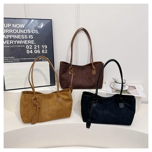 Trois sacs cabas en daim en kaki, marron et noir disposés sur des marches blanches