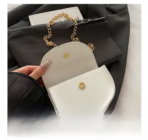 Detail showing high-quality golden magnetic buckle and chain strap on white mini bag