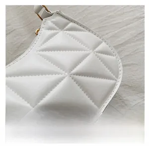 Détail macro du sac en cuir matelassé blanc avec surpiqûres et finitions dorées