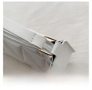 Détail du fermoir en métal doré et de la texture matelassée du sac à main blanc