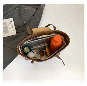 Vue détaillée du grand sac cabas marron contenant un ordinateur et des objets du quotidien