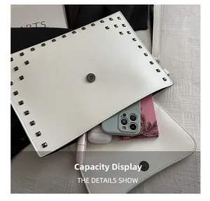 Interior capacity of white leather envelope bag with rivets showing storage for phone and makeup