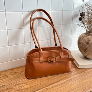 Vintage Umhängetasche in Karamellbraun mit Gold-Schnalle auf Holzoberfläche