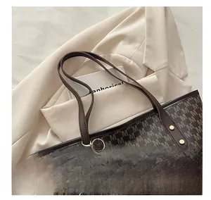 Detail of dark brown tote bag with M-print, leather handles and cloud charm detail