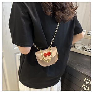 Detail of apricot crossbody bag with 3D cherry decor worn by a model in a home setting
