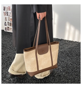 Détail du cabas beige avec bordure en cuir marron foncé et fermeture magnétique
