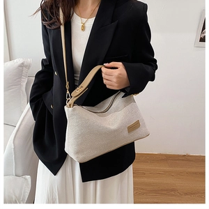 Dettaglio della trama in maglia beige con manico in pelle marrone e finiture in metallo