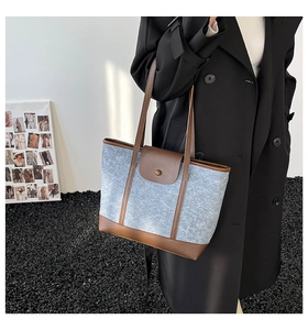 Détail du sac cabas en daim bleu avec poignées en cuir marron et fermeture à rabat magnétique