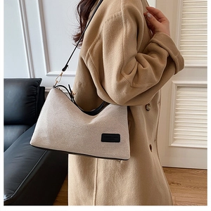Detail of cream canvas shoulder bag with black leather trim and chic fashion logo label