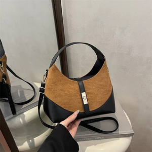 Retro two-tone leather bucket bag in brown suede and black, shown on a white table