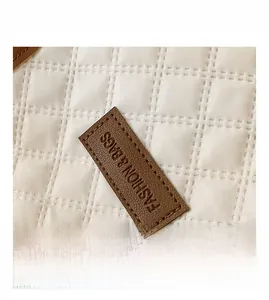 Macro view of quilted fabric texture and brown leather label with fashion lettering
