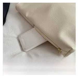 Detail showing the side pocket function of a beige lychee pattern leather tote bag