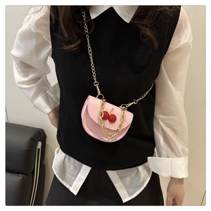 Pink saddle bag with red cherry detail and gold chain strap shown on a model