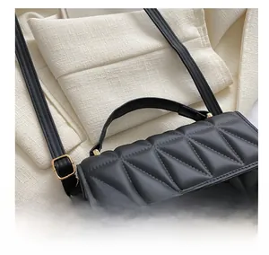 Detail of black quilted handbag with leather handle and decorative chunky chain strap