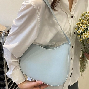 Sac hobo bleu clair en similicuir porté avec chemise blanche et fleurs de marguerite