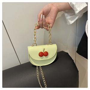Close-up of a mint green crossbody bag with cherry decor and gold chain strap
