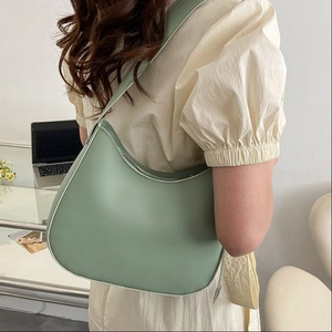 Sac hobo minimaliste en cuir vert clair porté par un mannequin avec un beau drapé