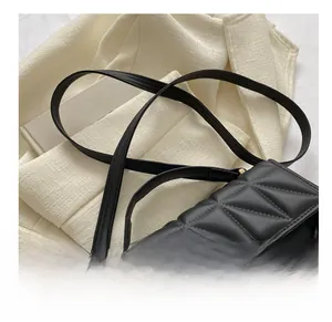 Detail of black quilted shoulder bag with chain strap and elegant faux leather texture