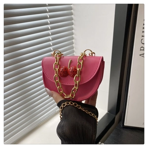 Detail of pink saddle bag with sparkling cherry rhinestone motif and gold chain strap