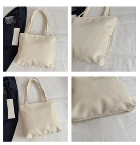 Close-up of litchi grain texture and metal zipper detail on cream large tote bag