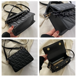 Detail view of black quilted crossbody bag showing internal capacity and metal chain