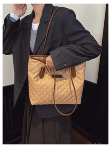 Quilted khaki tote bag featuring leather handles and brand label on a model's shoulder