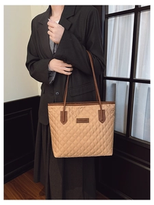 Close-up of quilted pattern and leather patch detail on a large beige tote bag