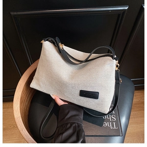 Dettaglio borsa tote in maglia beige con manici in pelle nera ed etichetta logo moda
