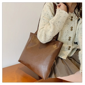 Close-up of deep brown tote bag with textured PU leather and elegant gold zipper details