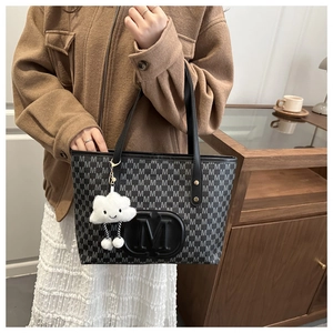 Detail of black tote bag with gray M-letter print and white plush cloud charm accessory