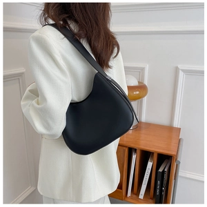 Modèle portant un sac hobo noir au design épuré et finitions métalliques argentées
