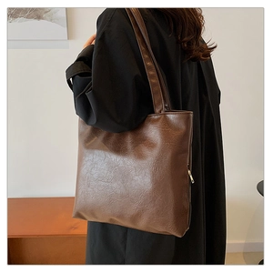 Detail of a brown vintage PU leather tote bag with side zipper and natural texture finish