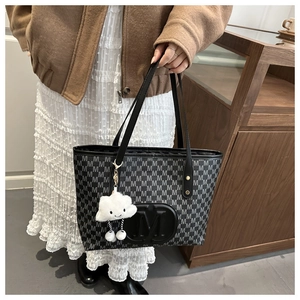 Detail of tote bag featuring monogram M print and plush white cloud charm on shoulder strap