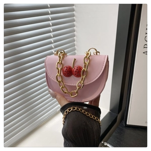 Detailed shot of pink leather mini bag featuring crystal cherry charms and gold chain