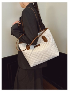 Detail view of quilted white tote bag with brown leather handles on model shoulder