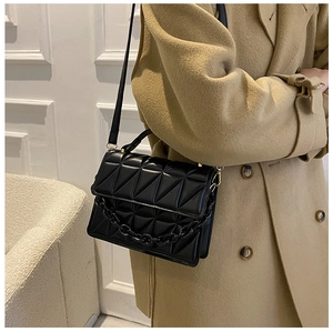 Detail of black quilted flap bag showing geometric stitching and matte chain strap