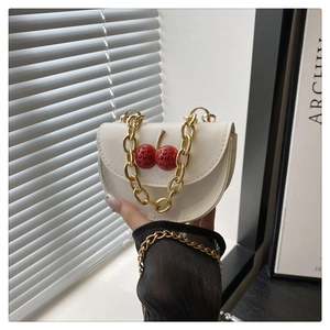 Detail of cream leather shoulder bag with red crystal cherry ornament and gold chain