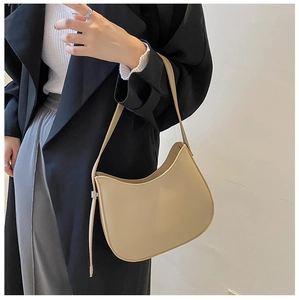 Gros plan d'un sac à bandoulière demi-lune beige minimaliste en cuir mat lisse