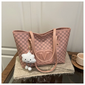 Pink monogram tote bag with embossed M logo and cloud charm on a cozy wool surface