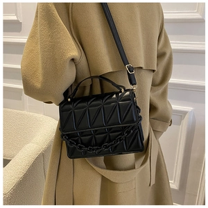 Fashionable black quilted crossbody bag with a decorative chain shown on a model