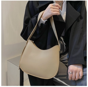 Sac hobo demi-lune beige chic porté avec un blazer noir pour un look minimaliste moderne