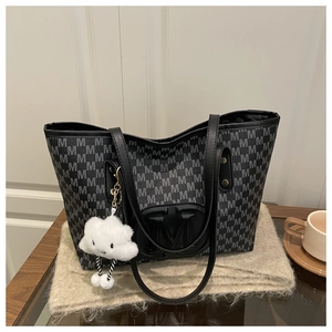 Close-up of black leather tote bag with monogram print and cloud plush pendant