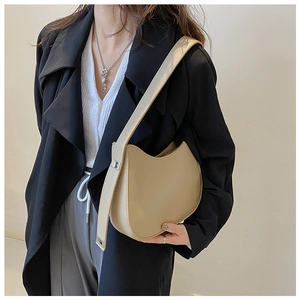 Détail d'un sac d'épaule demi-lune en cuir beige avec bandoulière large et métal argenté
