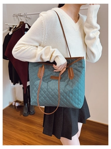 Detail of dark green quilted tote bag with brown leather straps and spacious interior