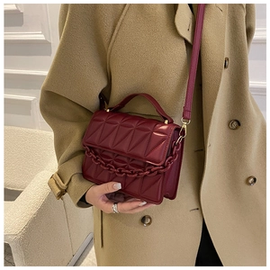Detail of burgundy quilted crossbody bag with oversized geometric stitching and chain handle