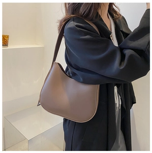 Détail porté d'un sac hobo marron foncé au fini épuré et design minimaliste chic