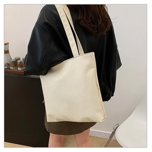Detail view of large off-white tote bag with double straps and leather-like texture