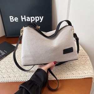 Borsa a spalla in maglia crema con cinturini in pelle nera su tavolo con pizzo
