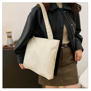 Detail view of cream-white PU tote bag showing soft texture and side zipper accent